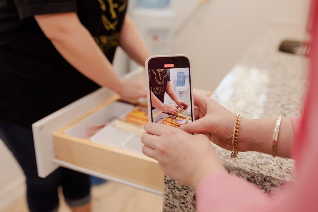 Recording a close-up of someone organizing a drawer of notary supplies, captured through the screen of a phone.